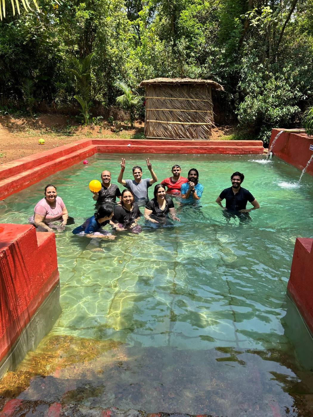The Goa retreat group waving together from a natural pool.